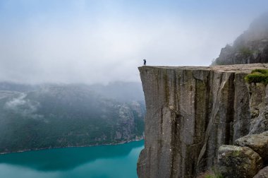 Tourist standing at Prekestolen rocks edge. clipart