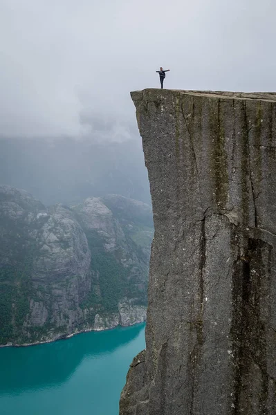 Kenar dikey fotoğraf 0f turist Prekestolen ayakta sallamak.