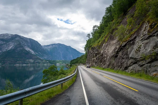 Strada panoramica norvegese tra acque del fiordo e ripide montagne — Foto Stock