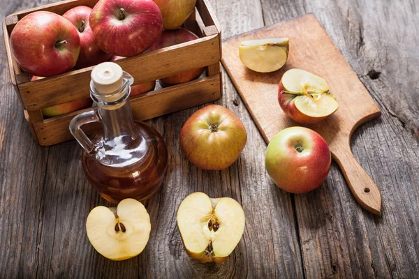 Apple cider vinegar and apples on a wooden table