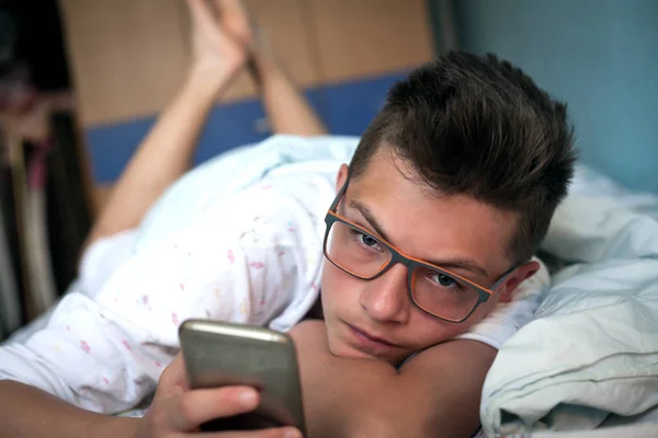 Teenager Lag Bett Und Benutzte Handy Stockbild