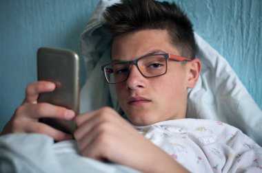 yatakta yatan ve smartphone kullanarak genç