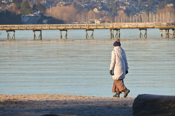 Eine Frau ist allein, während sie am ruhigen Ufer spaziert — Stockfoto