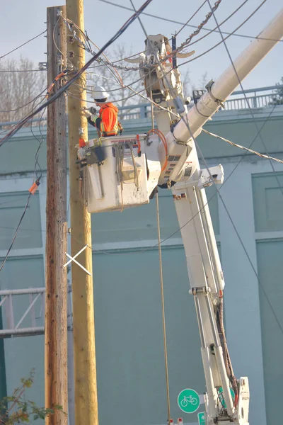 新しい水力発電ポールに生きている電気ワイヤーを離れて保つためセパレーターをインストールするバケットに立っている技術者のロング ショット — ストック写真