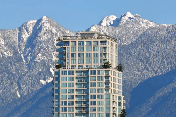 Ein Hohes Gebäude Steht Einem Sonnigen Tag Vor Schneebedeckten Bergen — Stockfoto