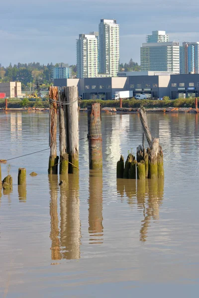 被用来保护渔船的旧的 腐烂的塔架很快就会消失在一个不断增长的城市的现代河边 — 图库照片