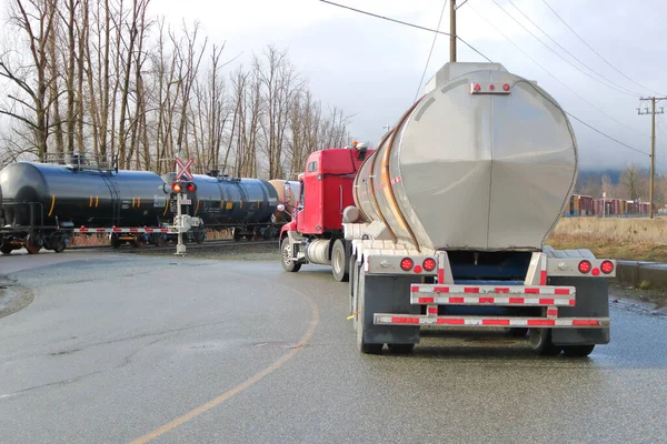An example of the different types of transportation used to transport dangerous fuels as train rail cars shipping chlorine pass a waiting semi trailer with petroleum.