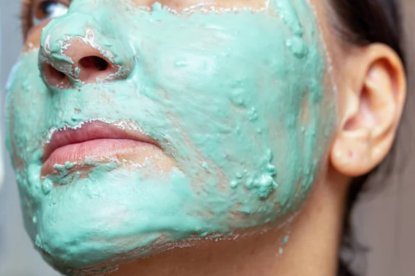 applying a green cosmetic clay mask on the attractive girl face