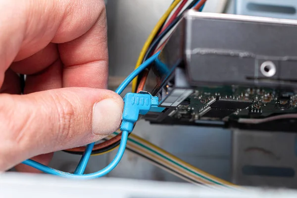 Connecting hdd drive disk sata cable with hand in the service. Maintenance, upgrade, installation.
