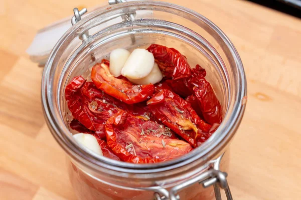 Homemade dried red  tomatoes slices with basil oregano spices in a glass jar. Traditional Italian Mediterranean kitchen cuisine.