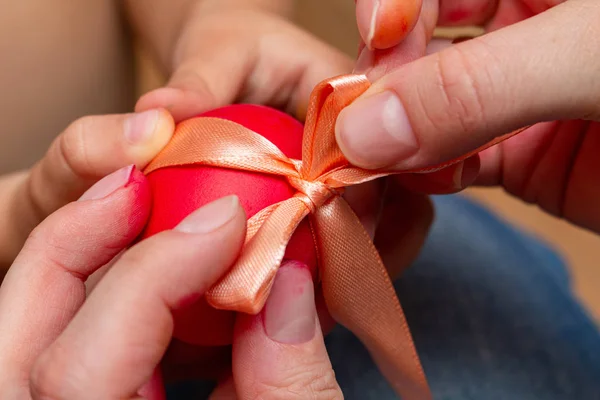 red egg with bow in hands for the Easter