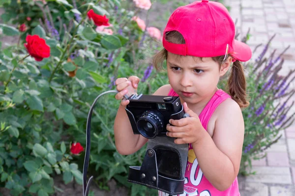 little girl shooting blog on retro photo camera close up.