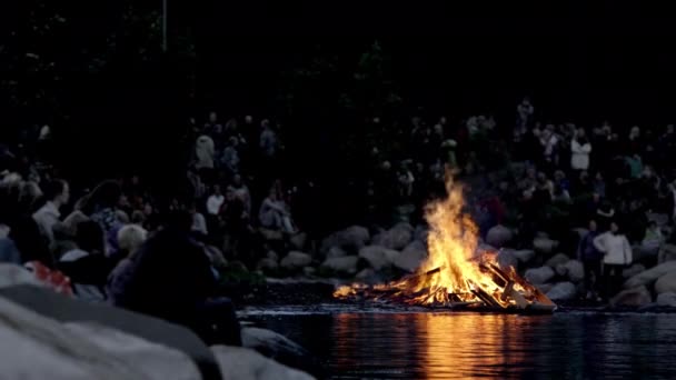 Θολή βολή μιας ομάδας ανθρώπων που συγκεντρώθηκαν γύρω από τη φωτιά κατά τη διάρκεια της καλοκαιρινής ημέρας — Αρχείο Βίντεο