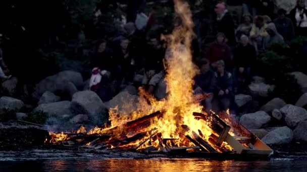 Średniej klasy stos z wysokimi płomieniami płonący nad brzegiem jeziora — Wideo stockowe