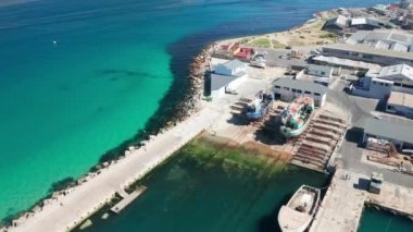 Kristal berrak suda yüzen teknelerle ve uçan kuşlarla iskelenin manzarası