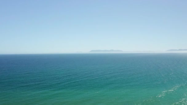 Pan Shot van een drone die over de oceaan vliegt en een uitzicht op het witte zandstrand — Stockvideo