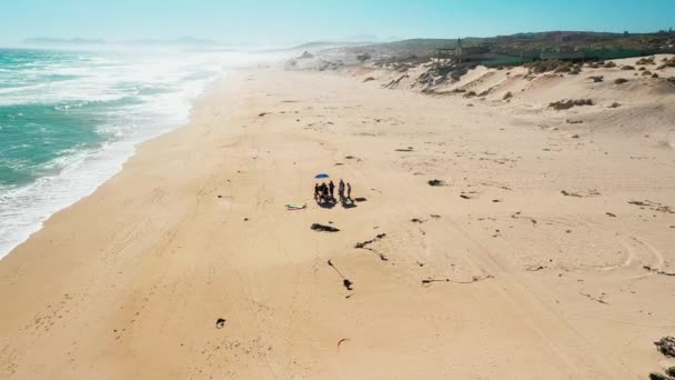 Drone Zooming Out egy csoport ember áll a tengerpart közepén — Stock videók