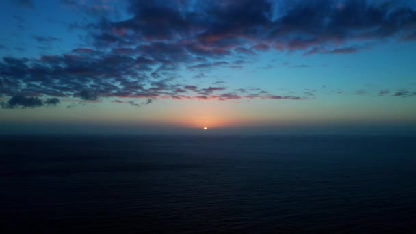 Dron unoszący się nad oceanem z widokiem na zachód słońca nad horyzontem — Wideo stockowe