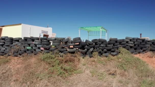 Tiro em órbita de pneus antigos empilhados em uma linha fora de uma garagem — Vídeo de Stock