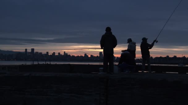 Силует чотирьох чоловіків, які ловлять рибу на воді ввечері на пляжі Єрихон. — стокове відео