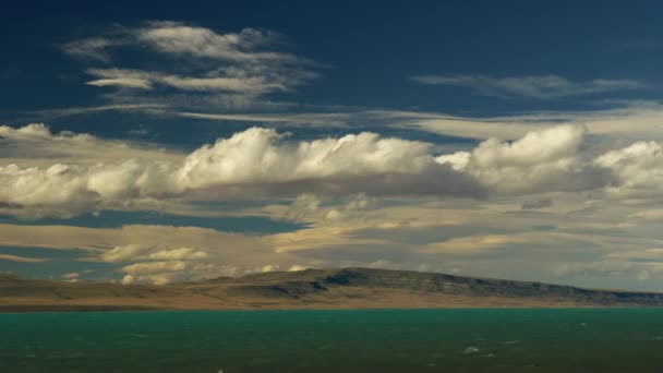 青い空とターコイズブルーの水の下で圧延雲とCalefate山 — ストック動画
