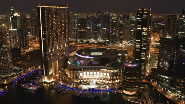 물 근처에 있는 현대식 건물의 시간 조절 장치와 밤에 도시의 조명을 보여준다 — 비디오
