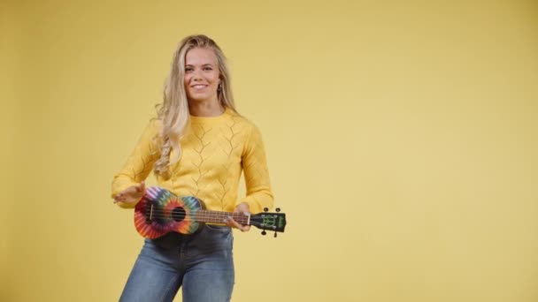 Glada kvinna Strumming och knacka en Ukulele med hennes smala händer — Stockvideo