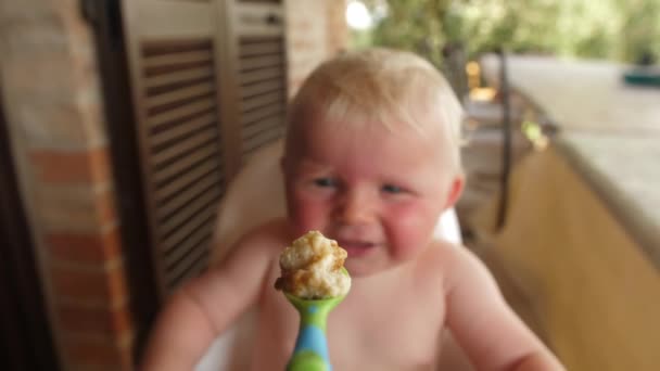 Tiro focado de um gordinho bebê menino comer a partir de uma colher — Vídeo de Stock