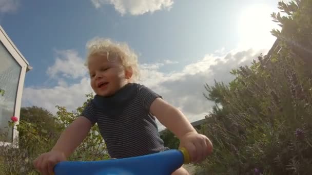 Spaß liebende Kleinkind auf seinem blauen Fahrrad durch den Hinterhof — Stockvideo