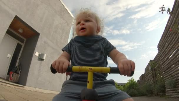 Low-Angle Front View van een peuter rijden zijn fiets op zijn achtertuin — Stockvideo