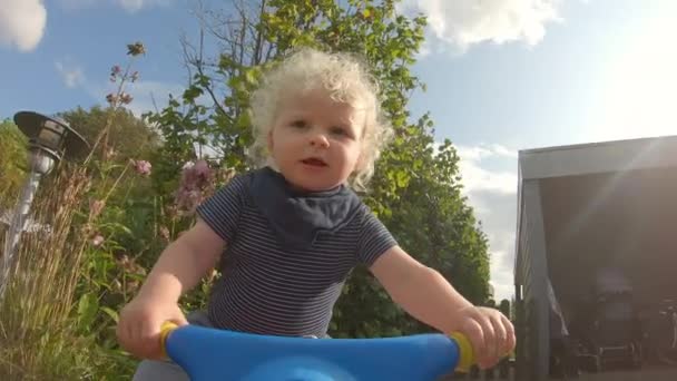 Low-Winkelaufnahme eines Kleinkindes, das sein Fahrrad fährt, während es ein schwarzes Latz trägt — Stockvideo