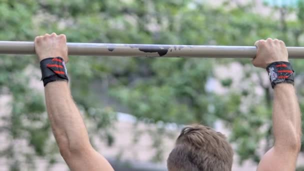 Выстрел в спину здорового человека, висящего на обезьяньем батончике во время покачивания мышц спины — стоковое видео