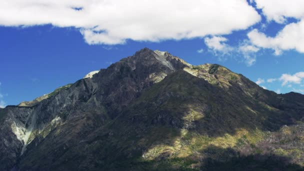 Tiro médio de um pico de montanha com nuvens rolando acima — Vídeo de Stock