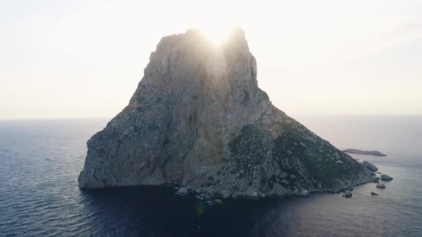 La luz del sol detrás de un alto acantilado en medio de las aguas del océano Ibiza — Vídeos de Stock
