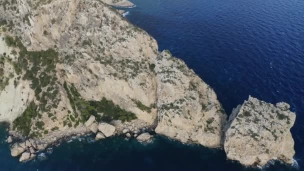 Disparo de drones orbitando alrededor del acantilado con aguas azules del océano rodeándolo — Vídeos de Stock