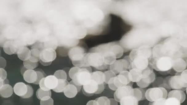 Sparkling Ocean Water in Bokeh Schot met een wazig uitzicht op een grote steen — Stockvideo