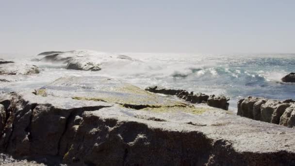 Пьестальный выстрел больших волн, врезающихся в скалистую береговую линию в летний день — стоковое видео