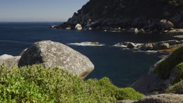 Pemandangan Pantai Rocky Sementara Kamera Panning Up to Reveal Langit Biru yang cerah — Stok Video