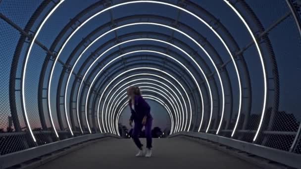 Танцовщица с светлыми волосами, танцующая в центре моста — стоковое видео