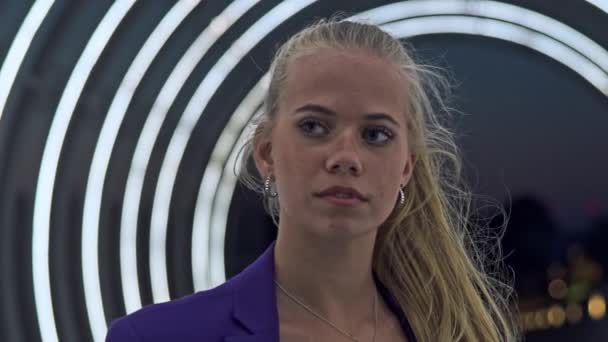 Modelo adolescente de moda que usa la parte superior e inferior púrpura que empareja parado a lo largo de un túnel de luz abierto — Vídeos de Stock