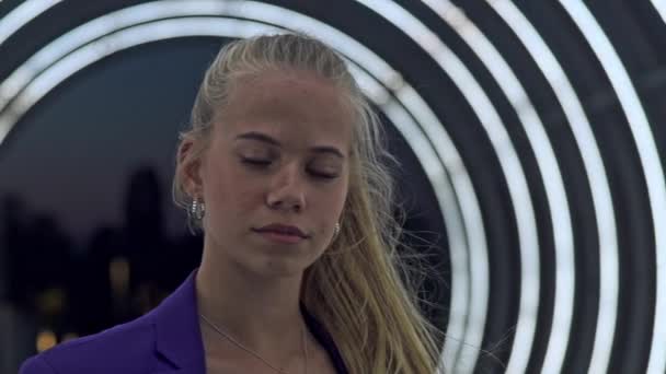 Fokuserad fotografering av ung blond modell stående på gatan och en bild av runda ljus i bakgrunden — Stockvideo