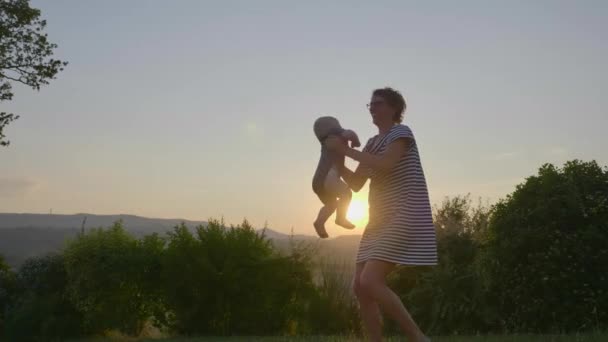 Взгляд веселой матери, горланящей и вылавливающей в воздух своего маленького ребенка — стоковое видео