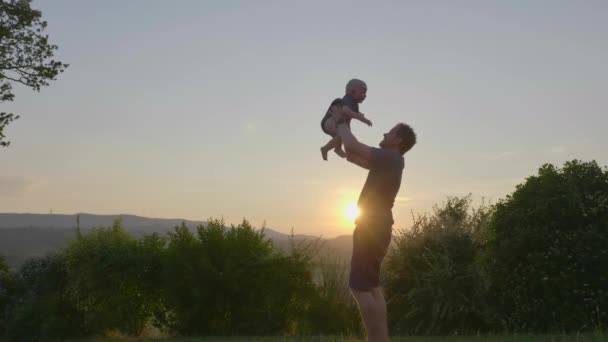 Blick auf einen hingebungsvollen Vater, der sein Baby spielerisch wegwirft und einfängt — Stockvideo