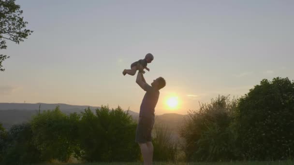 Energischer Vater spielt mit seinem kuscheligen kleinen Jungen, während er ihn in die Luft hebt — Stockvideo