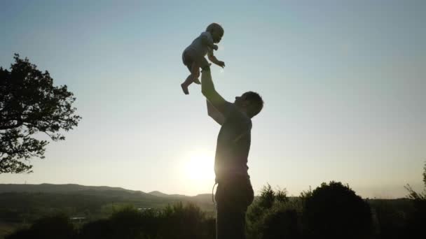 Сильный отец бросает своего сына в воздух, а затем осторожно ловит — стоковое видео