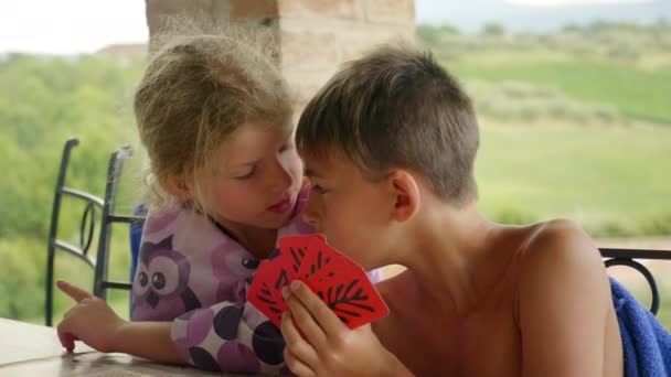 Schattig meisje en jongen praten en spelen met rode kaarten Outdoor — Stockvideo