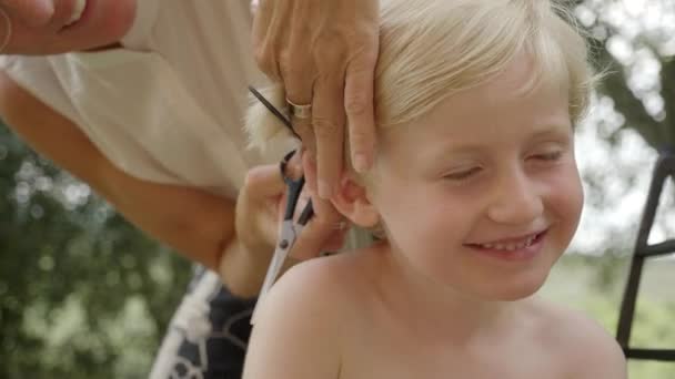 Mladý kluk má vlasy ostříhané jeho matkou — Stock video