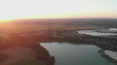 Cinematic Aerial Shot of Lake and Lush Green Fields During Sunset