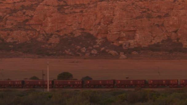 Seguindo Tiros de Carga em uma Ferrovia ao lado de Montanhas Rochosas — Vídeo de Stock