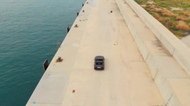 Ferrari Cruising by the Docks with Wavy Ocean Waters on its Left